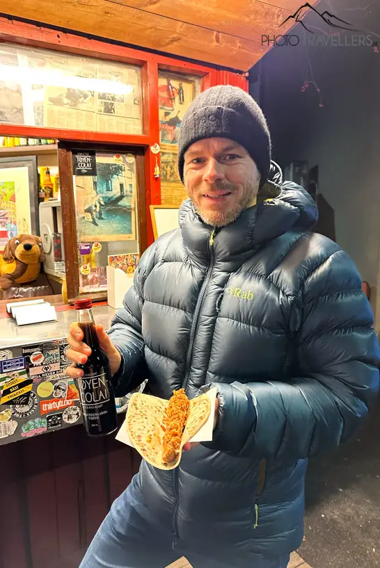 Reiseblogger Flo mit einer Cola und einem veganen Hotdog vor dem Hotdogstand Syverkiosken in Oslo 
