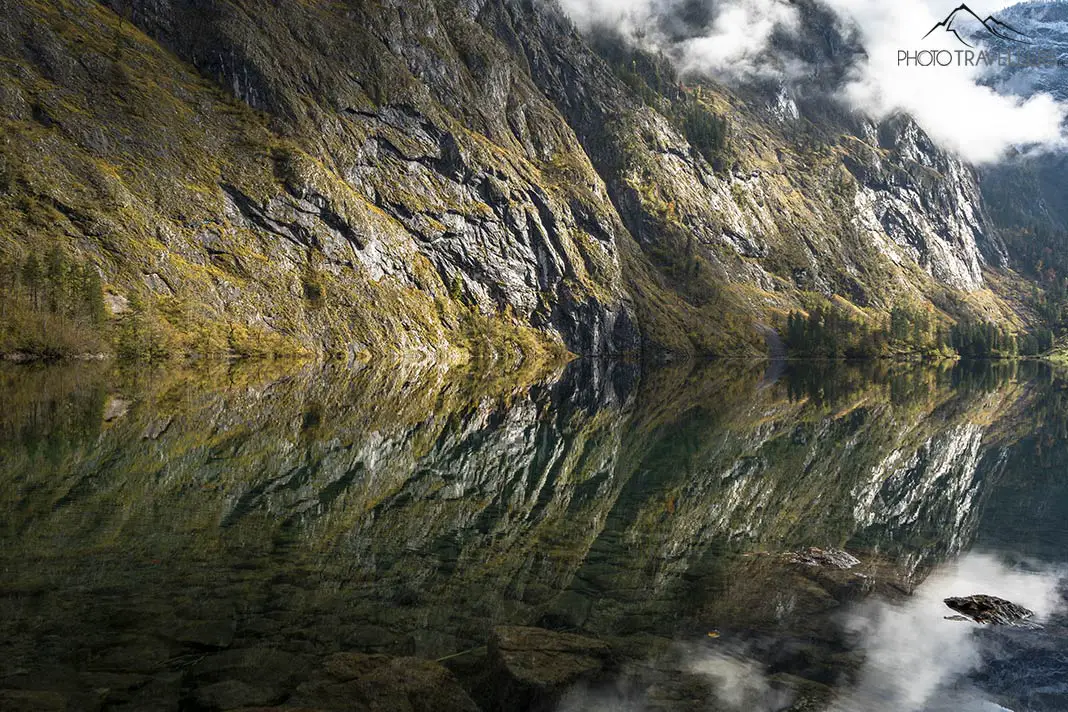 A wall of rock is reflected in the water of the Obersee lake