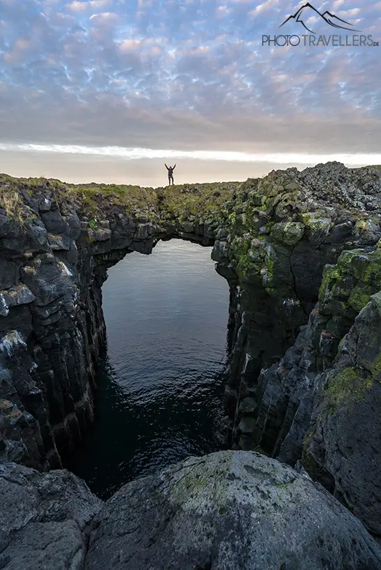 Reisebloggerin Biggi Bauer auf einem riesigen Felsbogen im Meer an der Küste von Arnarstapi in Island