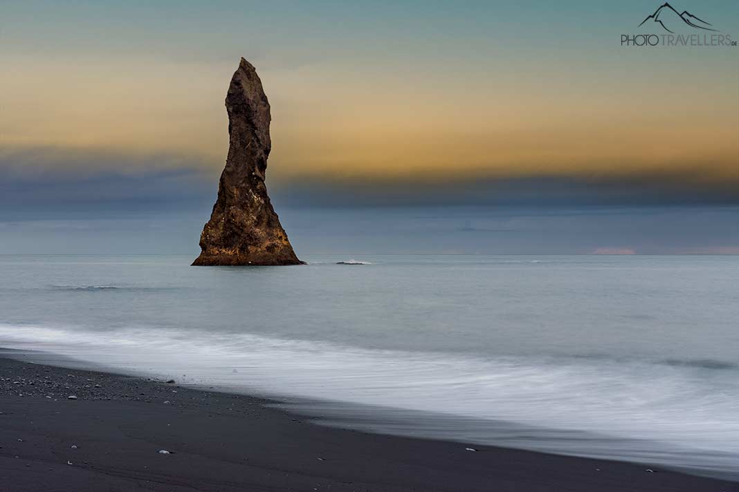 Ein spitzer Felsen im Meer am Strand von Reynisfjara in Island