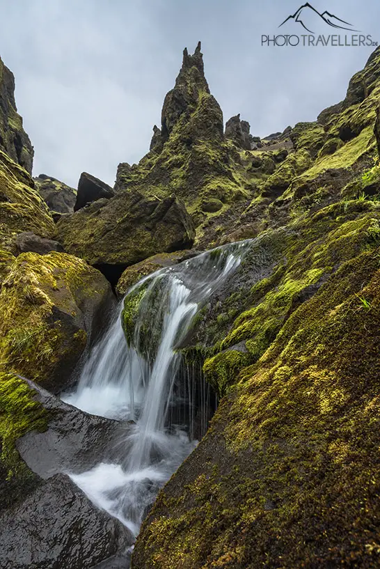 Ein Wasserfall mit einer Felsspitze im Tal Þakgil in Island