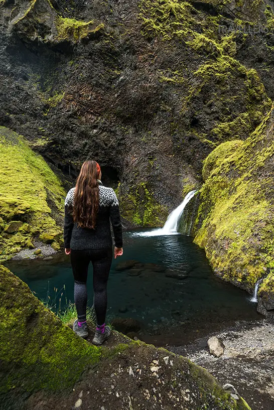 Biggi vor einem kleinen See mit Wasserfall im Tal Þakgil in Island