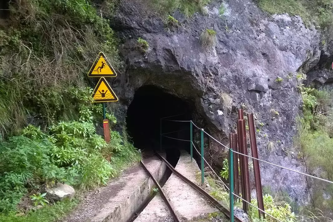 Zwei alte Schienen führen in einen Tunnel 