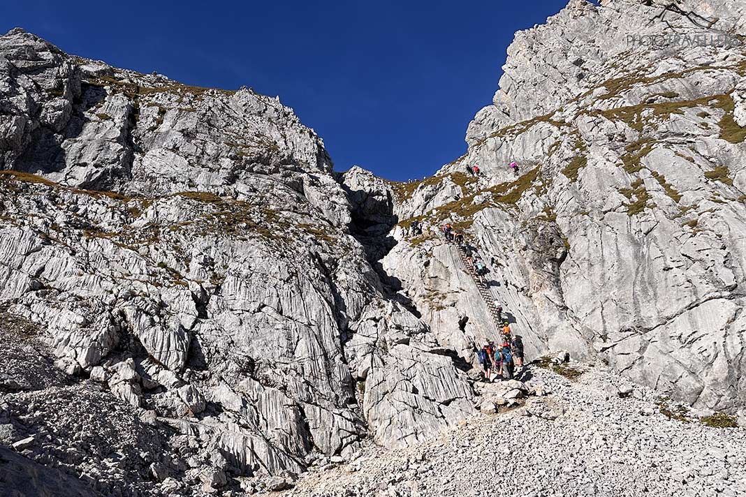 Klettersteiggeher vor der bekannten senkrechten Wand auf dem Weg zur Alpspitze