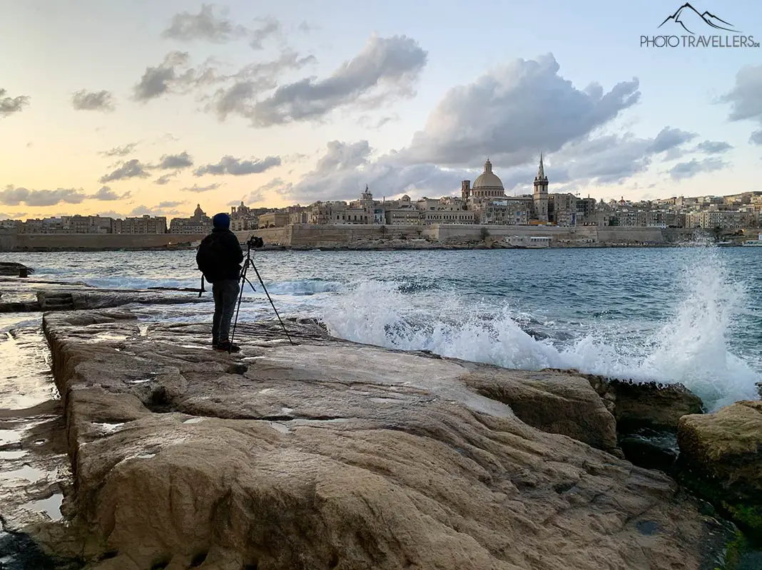 Fotograf am Morgen mit dem Stativ an der Küste auf Malta