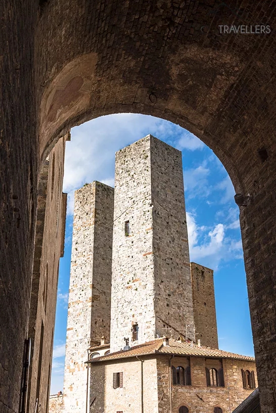 Der Blick durch einen Torbogen auf die Torri dei Salvucci in San Gimignano