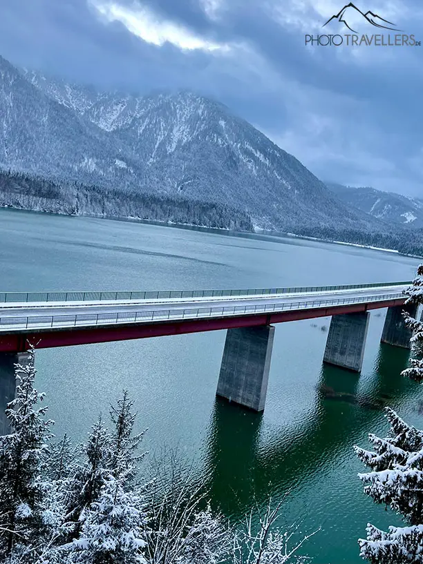Eine Brücke über einen Bergsee in den Alpen mit einem schiefen Horizont