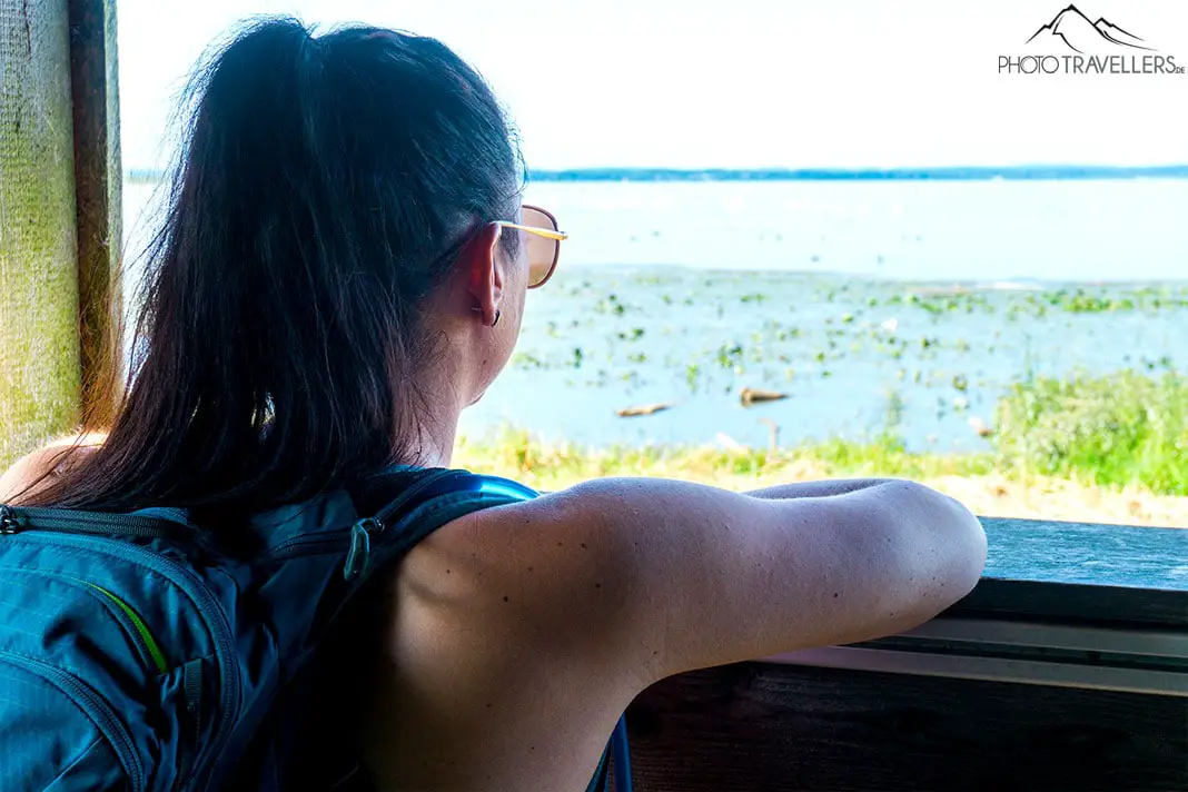 Reisebloggerin Biggi Bauer im Vogelbeobachtungsturm Achendamm mit Ausblick auf die Hirschauer Bucht am Chiemsee