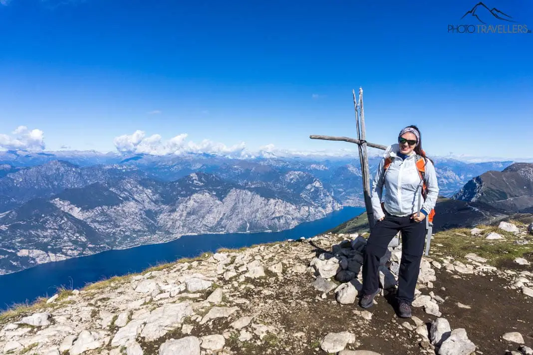 Reisebloggerin Biggi Bauer an einem Kreuz auf dem Monte Baldo mit Blick auf den Gardasee
