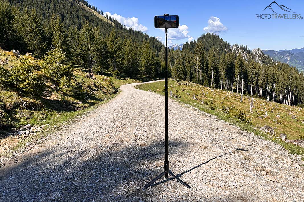 Das Toneof Selfiestick-Stativ aufgestellt auf einem Weg in den Bergen, voll ausgefahren mit einem Smartphone