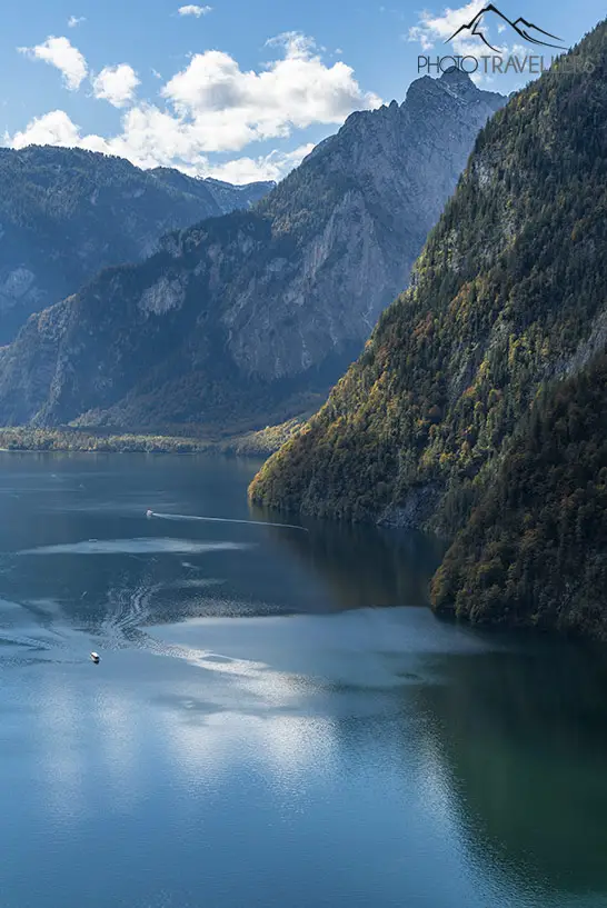 Der Blick auf den Königssee in Bayern. Auf dem See neben einer Felswand fährt ein Boot