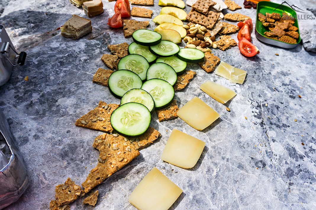 Knäckebrot, Käse, Gurken und Tomaten ausgebreitet auf einem Stein