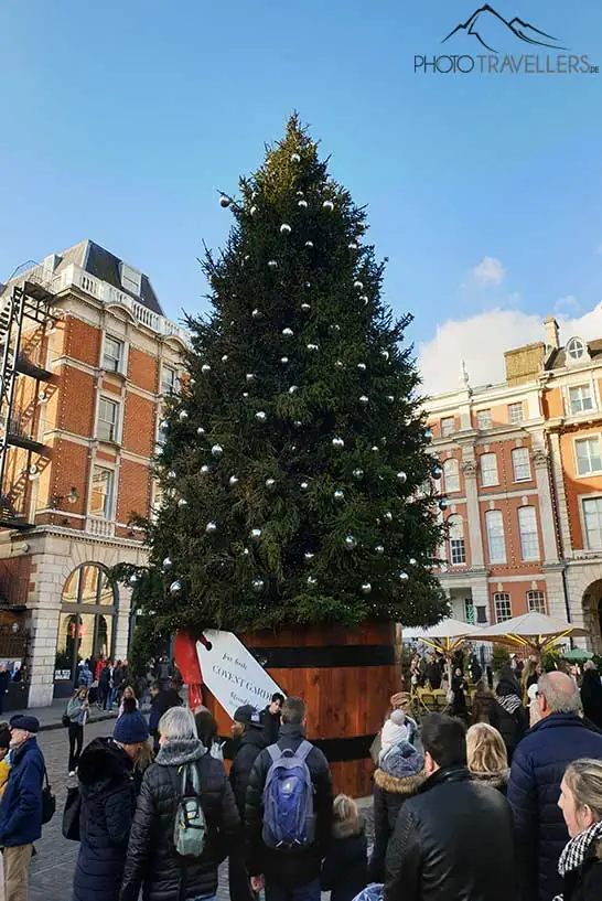 Menschen stehen vor dem hohen Christbaum am Covent Garden
