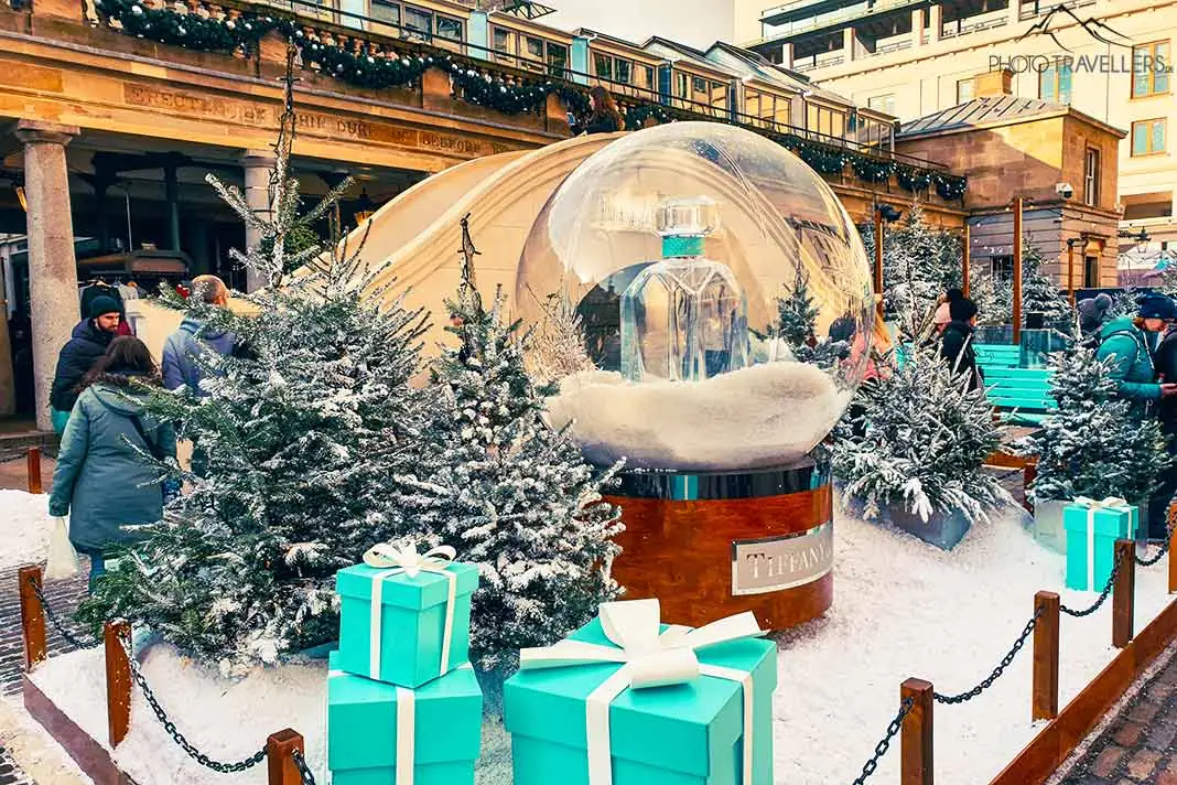 Eine riesige Glaskugel, Geschenkpakete und Kunstschnee sorgen für Weihnachtsstimmung am Covent Garden