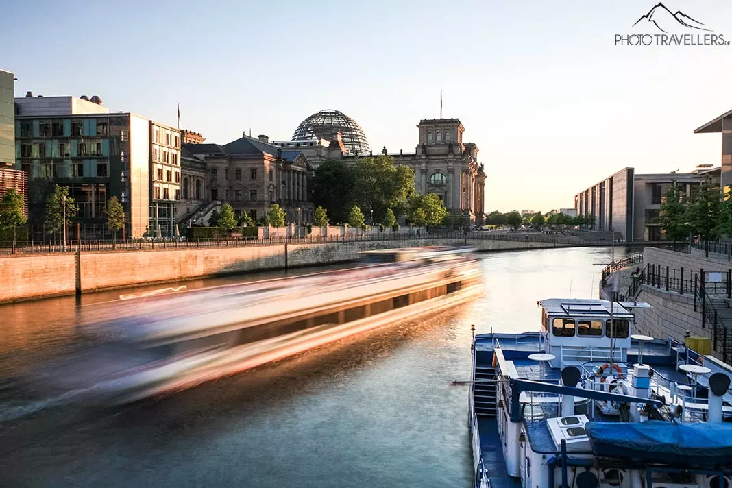 Der Blick über die Spree mit einem Boot auf das Reichstagsgebäude in Berlin