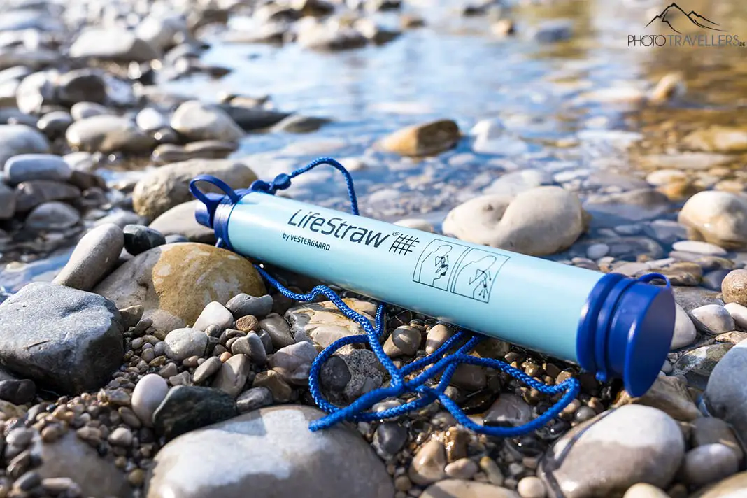 Ein portabler Wasserfilter von Lifestraw zwischen Steinen am Fluss