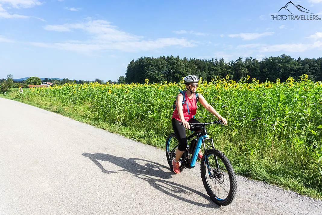 Reisebloggerin Biggi Bauer mit dem Fahrrad auf dem Chiemsee Radweg vor Sonnenblumen