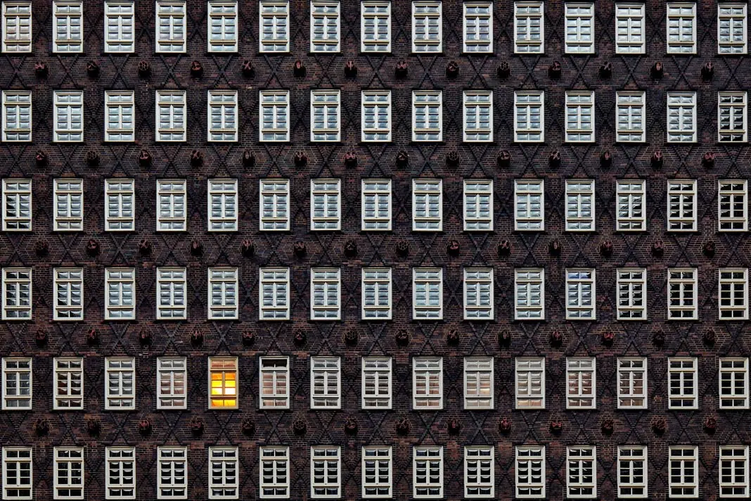 Eine Hauswand mit vielen Fenstern, eines ist beleuchtet