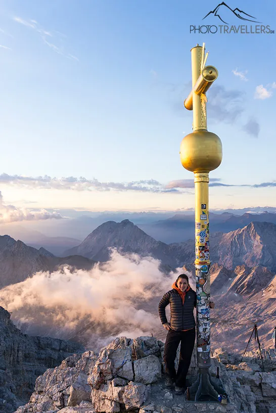 Reisebloggerin Biggi Bauer am Abend am goldenen Gipfelkreuz der Zugspitze