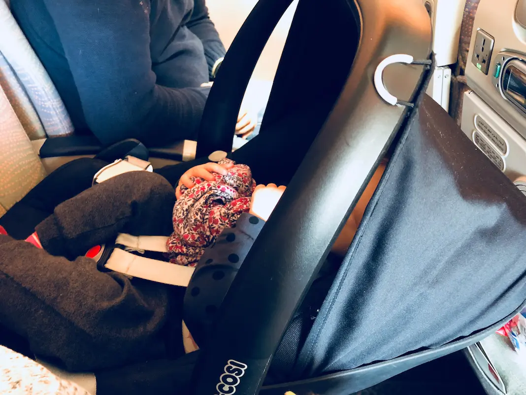 Baby im Maxicosi auf dem Flugzeugsitz