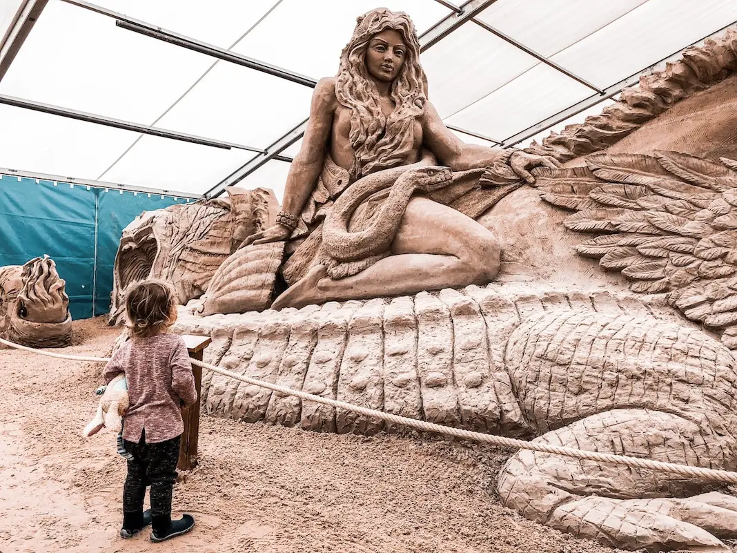 Kind vor einer Sandskulptur 