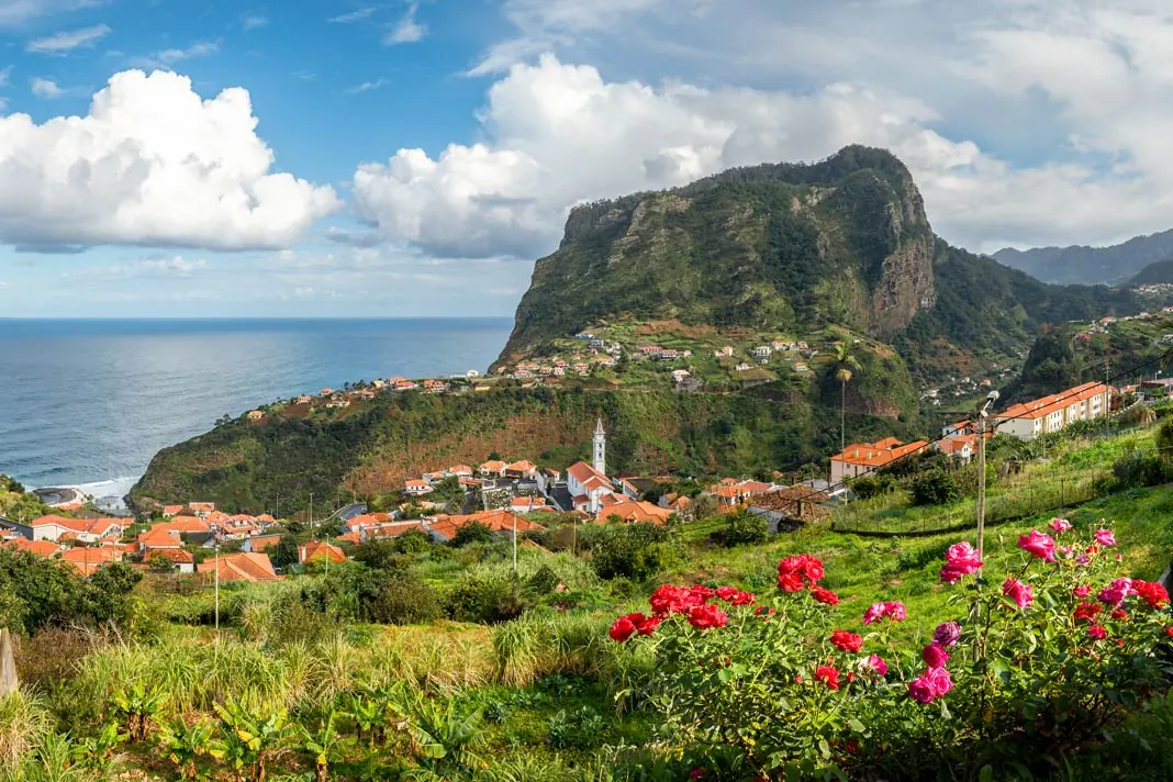 Rote Blumen, ein Dorf und der Adlerfelsen auf Madeira