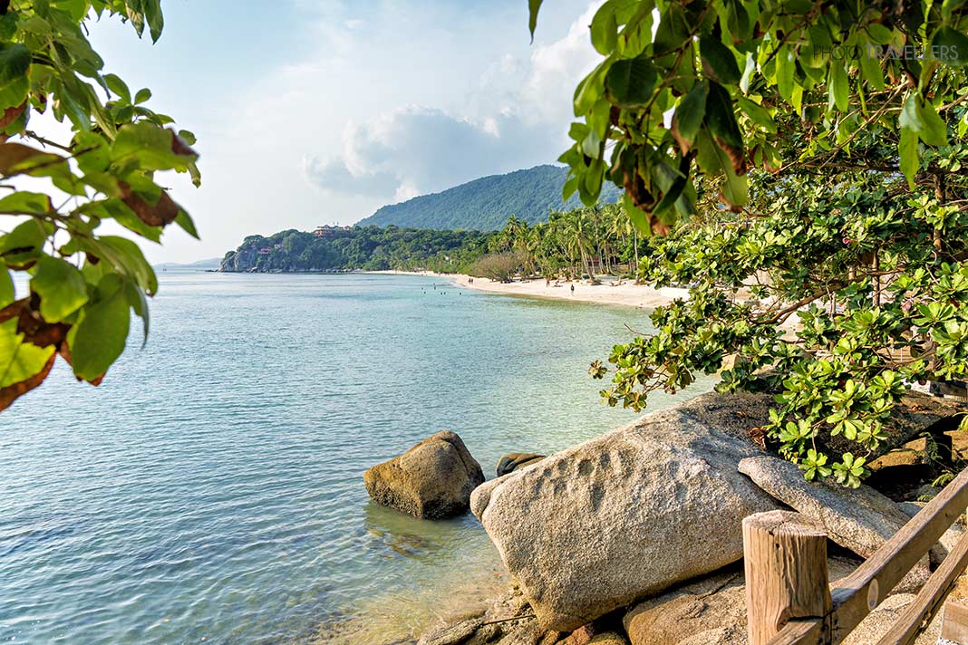Blick durch Bäume auf den Rin Nai Beach auf Koh Phangan, Thailand