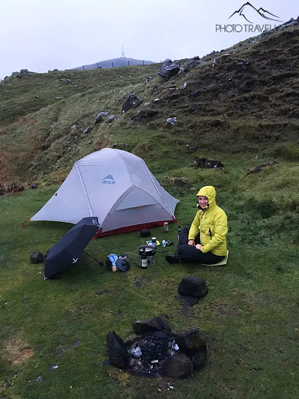 Biggi mit einem Campingkocher vor dem Zelt in Schottland