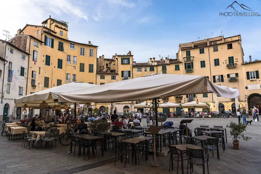 Stühle und Tische eines Restaurants auf dem Piazza dell'Anfiteatro in Lucca