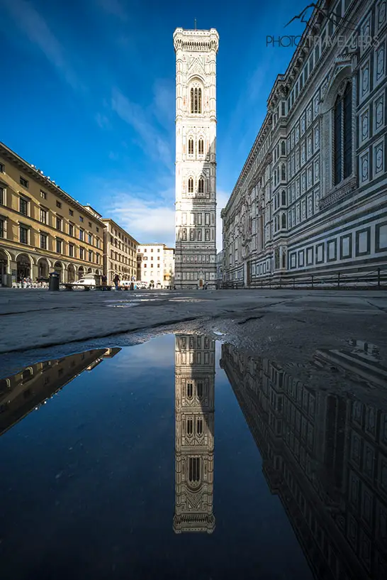 Der Glockenturm Campanile di Giotto spiegelt sich in einer Wasserpfütze