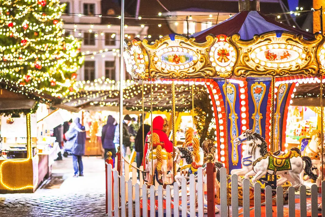 Blick hinein in den Weihnachtsmarkt Köln mit beleuchtetem Kinderkarussell