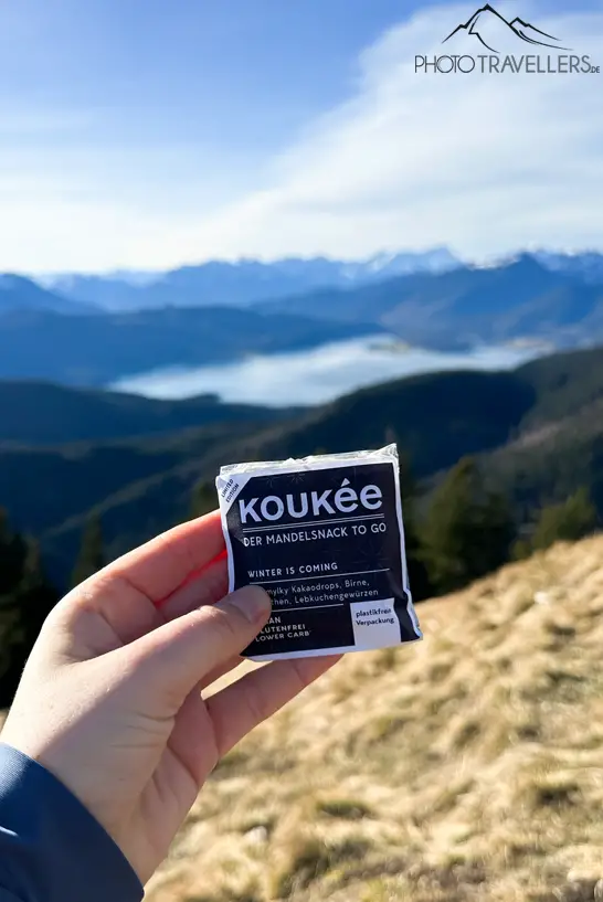 Ein Koukée-Mandelsnack vor einer Bergkulisse mit Bergsee