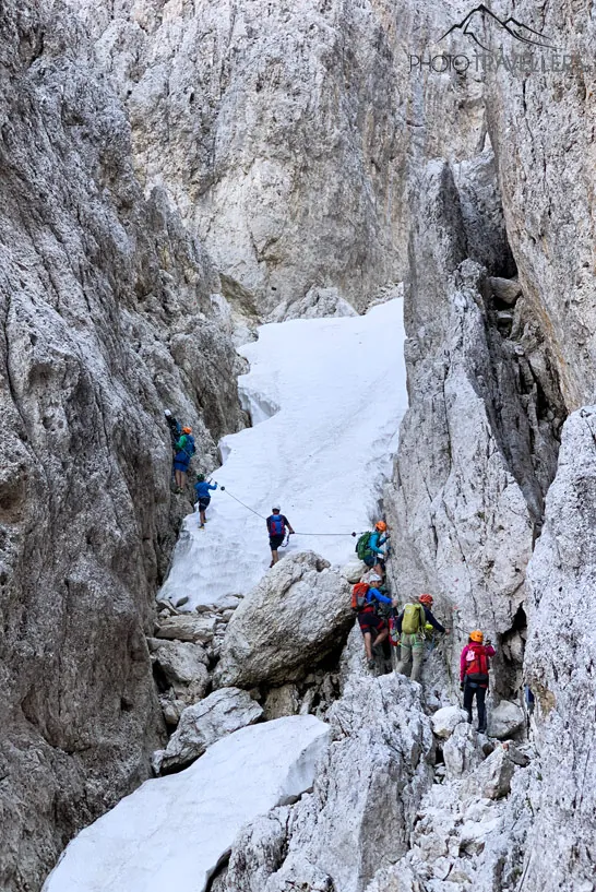 Klettersteiggeher auf einem Schneefeld auf dem Santnerpass-Klettersteig