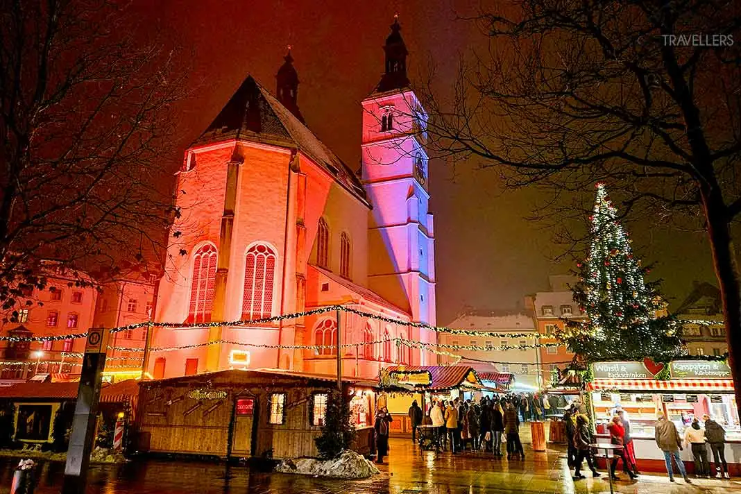 Weihnachtsbuden reihen sich um die beleuchtete Neupfarrkirche in Regensburg