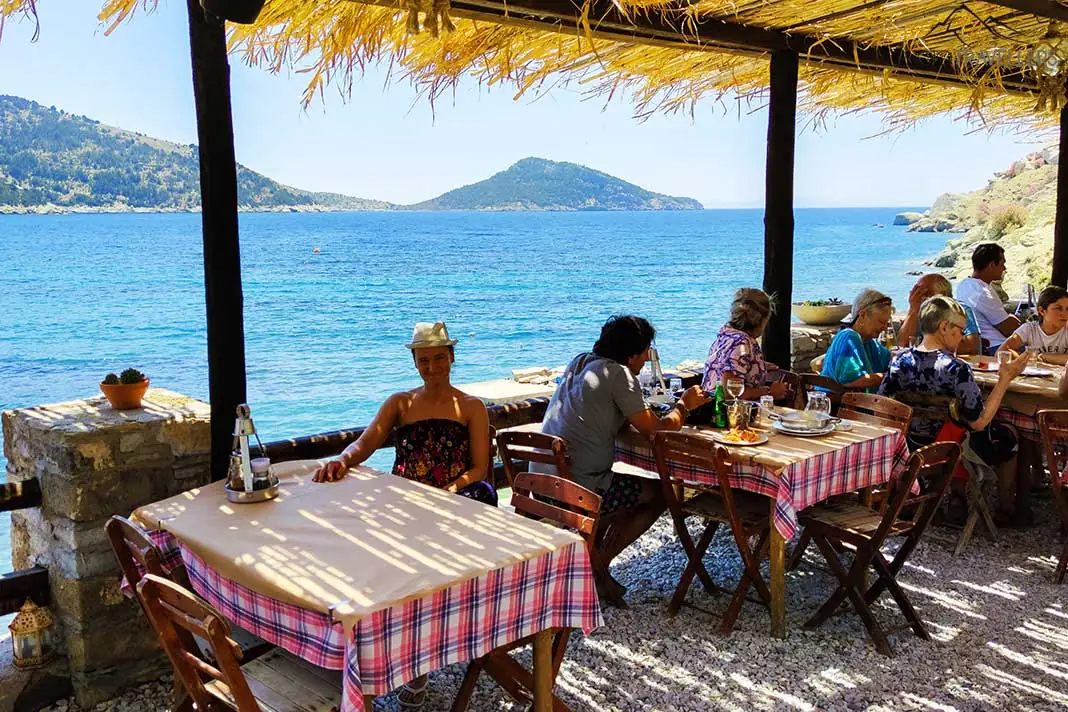 Gäste sitzen an den Tischen einer Taverne am Meer 