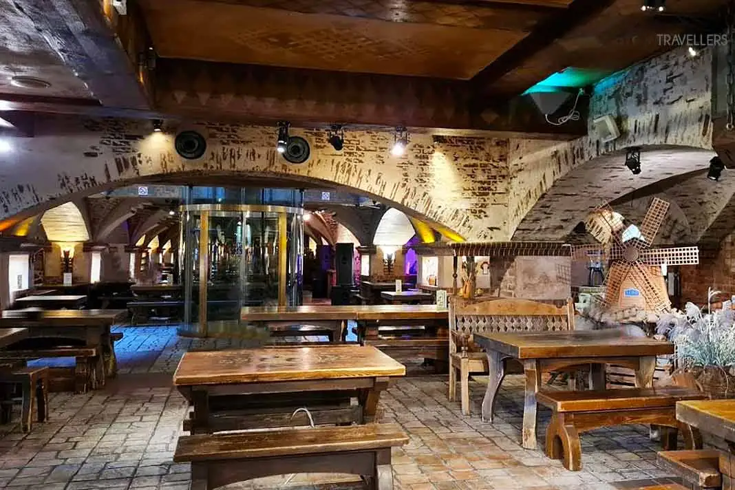 Leere Holztische stehen in einem großen Kellergewölbe im Lido Selbstbedienungsrestaurant in Riga