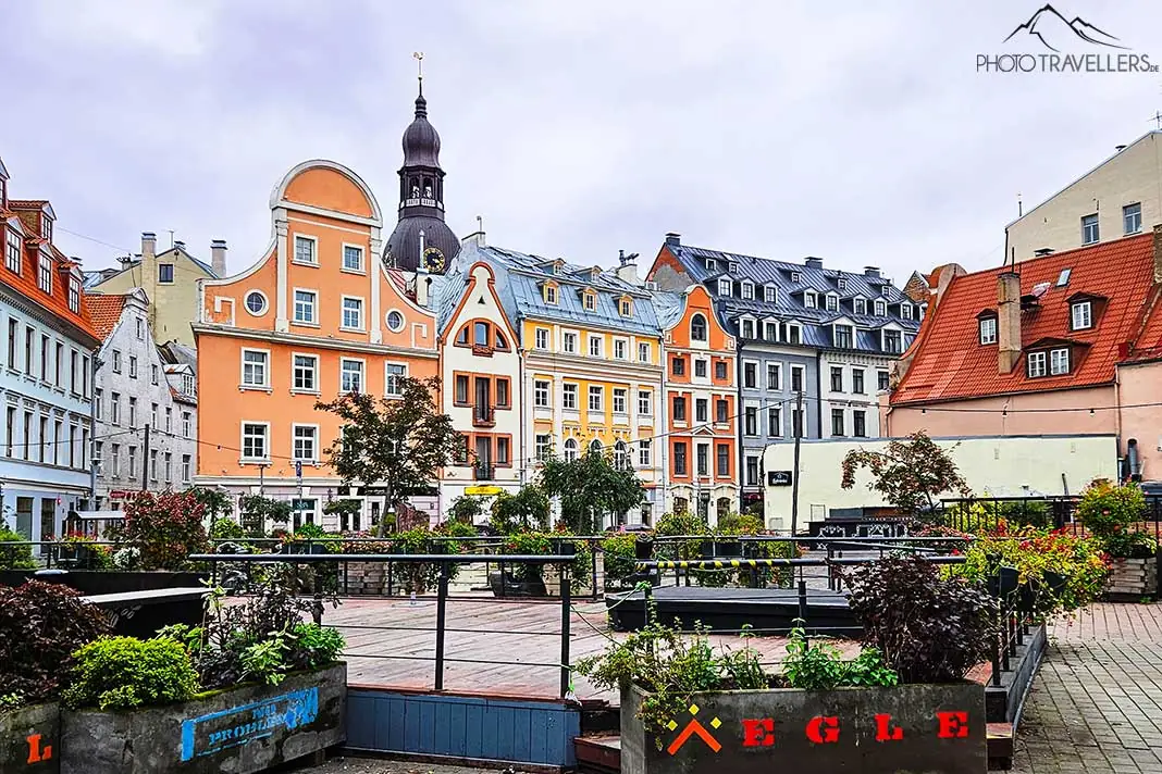Ein Kirchturm ragt zwischen bunten Häuserfassaden in der Altstadt von Riga heraus
