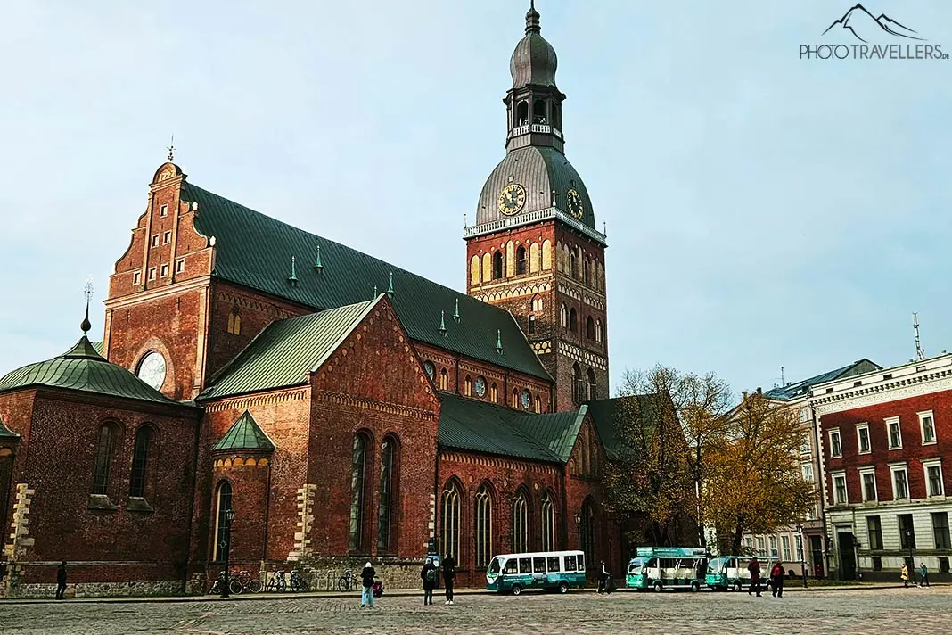 Mehrere Touristenbusse parken vor dem aus rotem Backstein erbauten Dom von Riga
