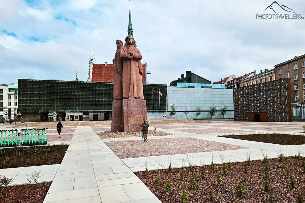 Marmorstatue mit drei Personen vor der dunklen Fassade des lettischen Okkupationsmuseums