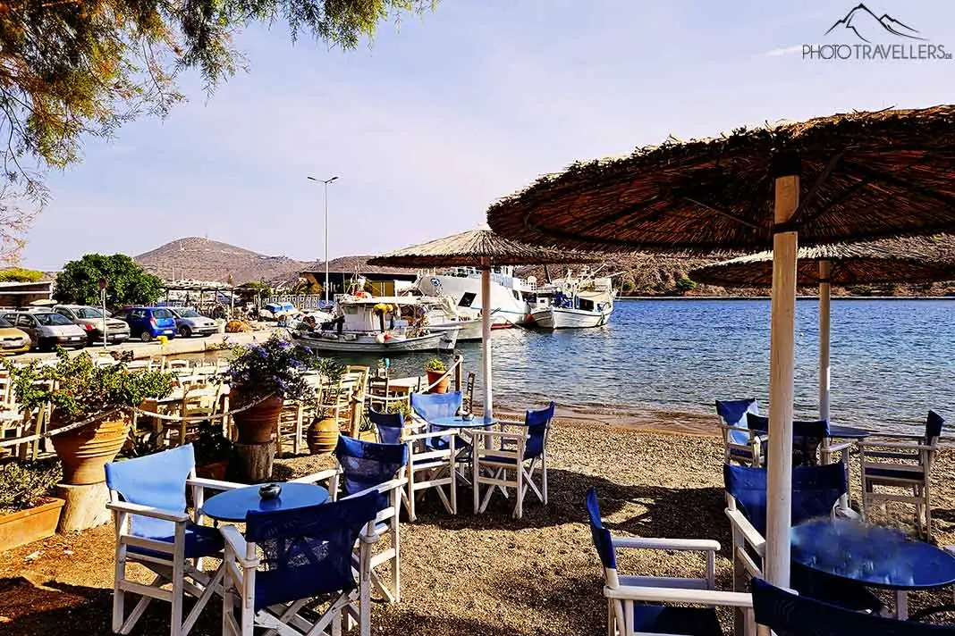 Leere Stühle und Tische stehen im Sand des Hafens von Skala auf Patmos