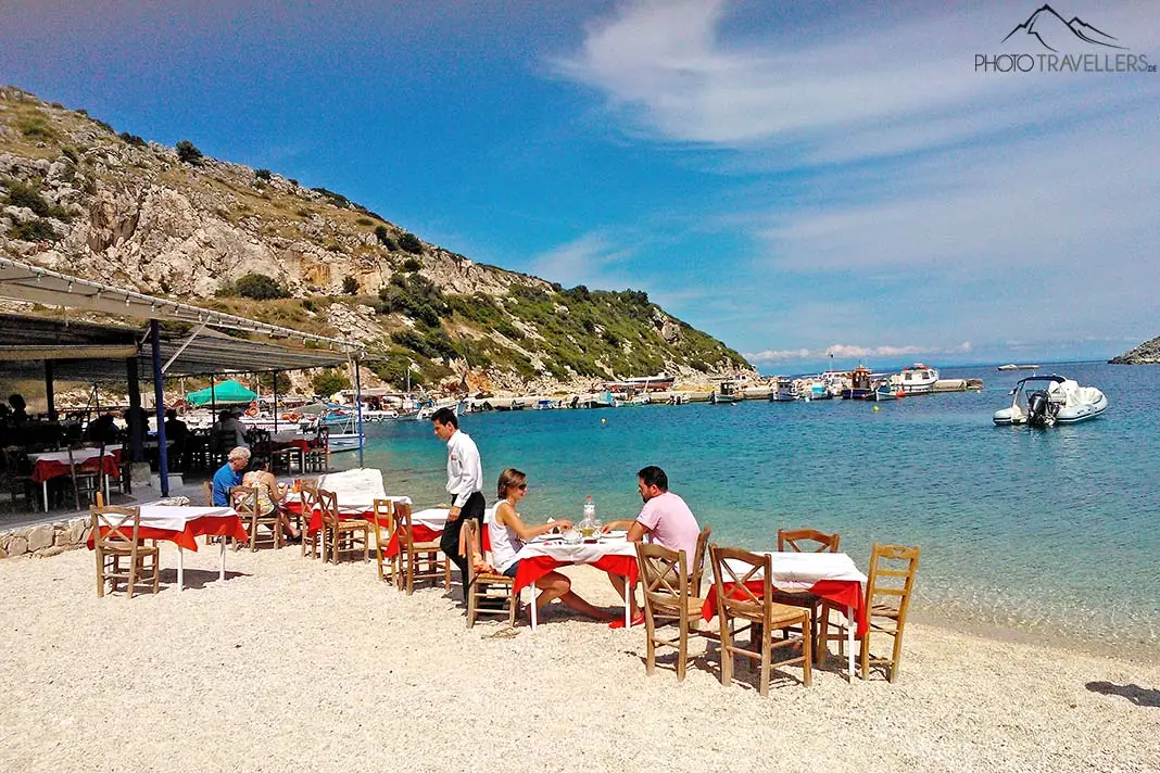 Gäste sitzen an den Tischen einer Taverne am Strand von Agios Nikolaos