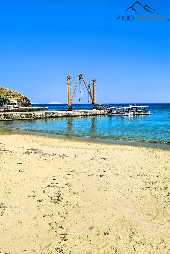 Auf dem Steg im Hafen von Moutsouna stehen zwei alte Verladekräne und davor ein kleines Boot