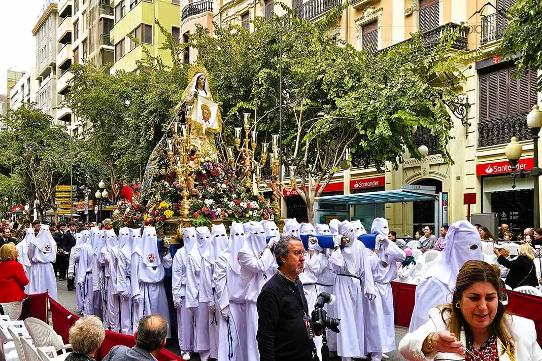 Mit weißen Schleiern gekleidete Teilnehmer einer Prozession stemmen einen Altar