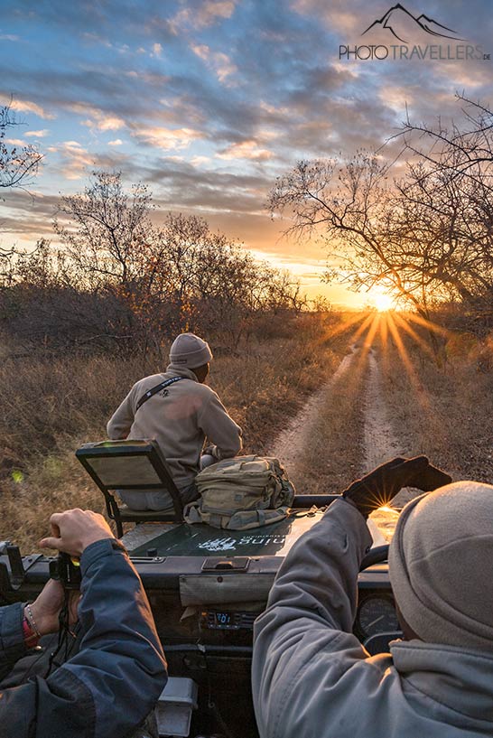 Der Blick über die Motorhaube des Safari-Geländewagens mit unserem Guide. Am Horizont sieht man die Sonne untergehen