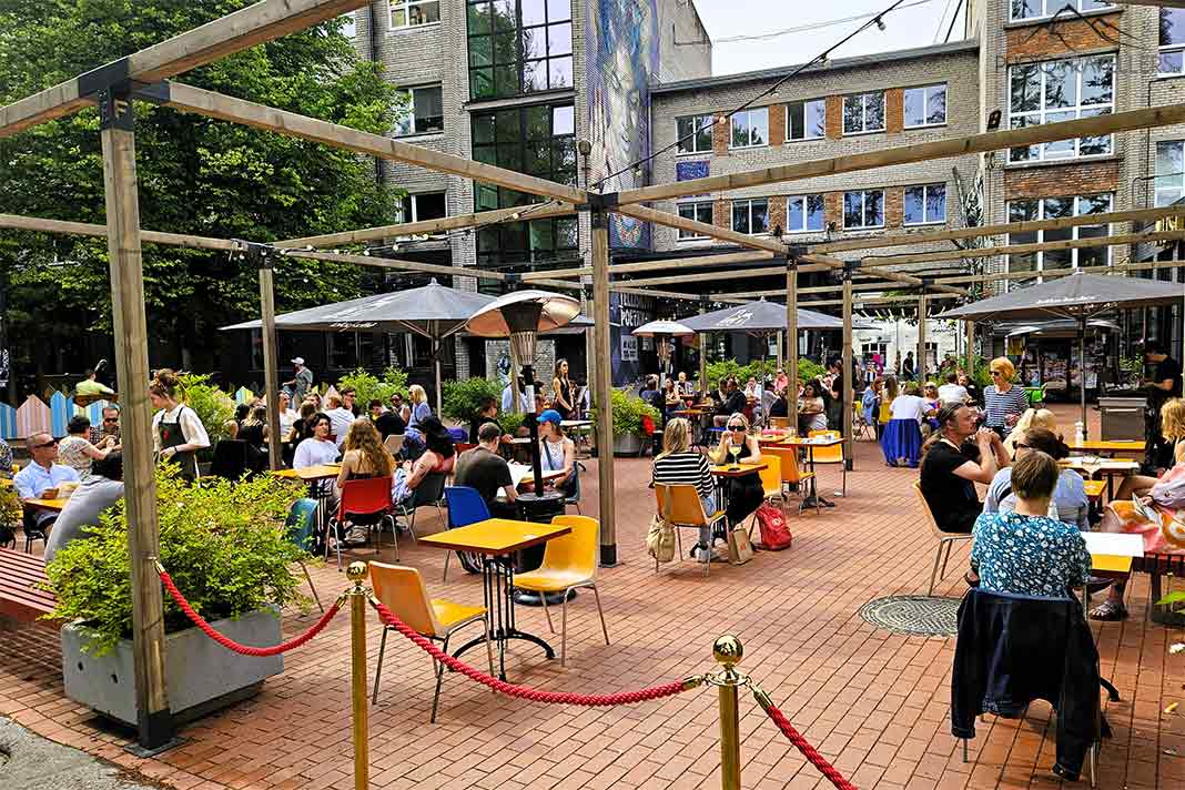 Gäste sitzen im Freien in einem Cafè im Tallinner Szeneviertel Telliskivi