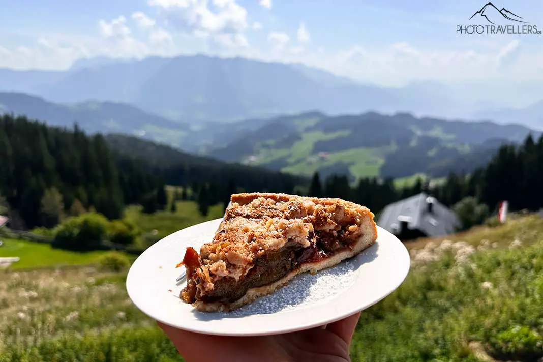 Ein Zwetschgenkuchen auf einem Teller, dahinter die Berge