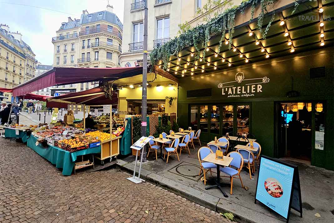 Leere Tische und Stühle eines Straßencafés und ein benachbarter Gemüsestand auf der Rue Mouffetard