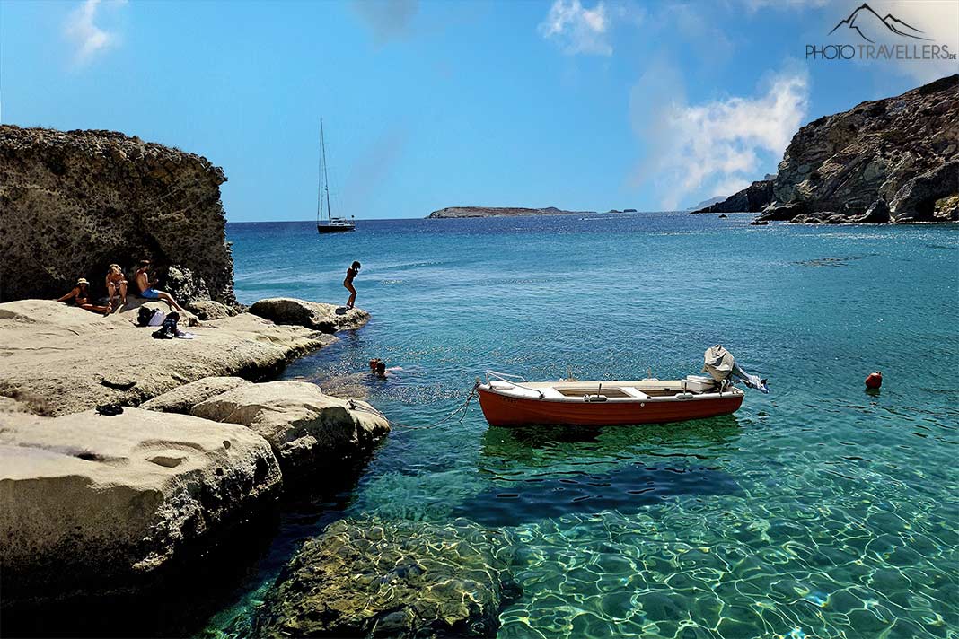 Ein kleines Boot und einige Badegäste liegen vor den kleinen Felsen und dem türkisfarbenen Meer in der Bucht von Goupa Kara