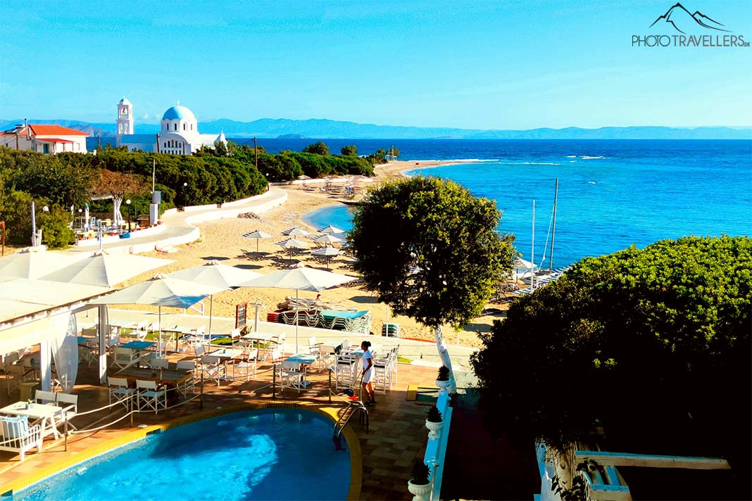 Der Sandstrand und die Kirche von Skala mit grünen Bäumen und Pool