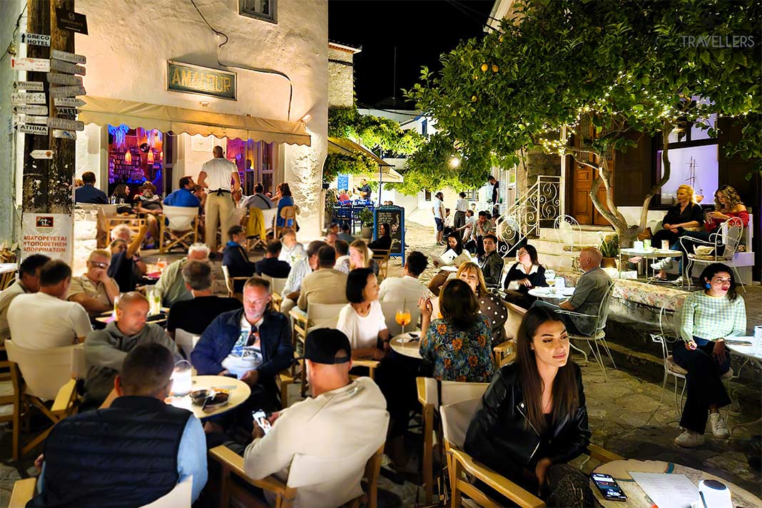 Viele Menschen sitzen in der Nacht vor den Bars in den engen Gassen der Altstadt von Hydra
